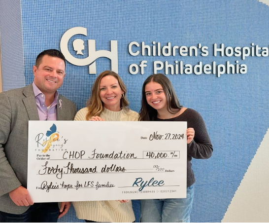 Ryan, Crystal, and Madison holding a large check made out to CHOP for $40,000