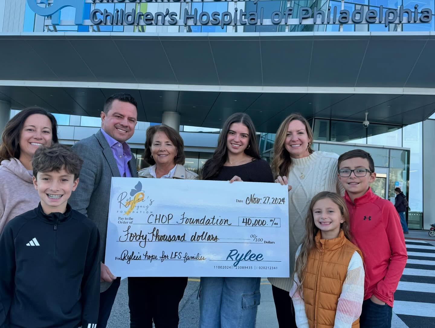 Ryan, Crystal, Madison, and others holding a large check to CHOP for $40,000